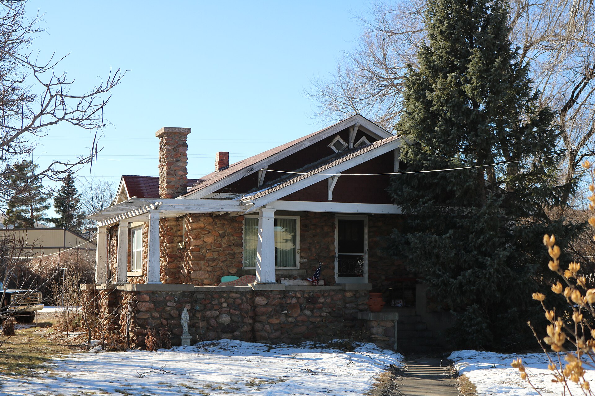 Exposed rafter tails and triangular knee braces under the low-pitched gable